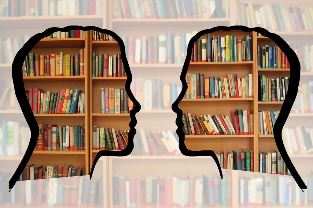 Dos siluetas mirándose a la cara con libros de fondo.